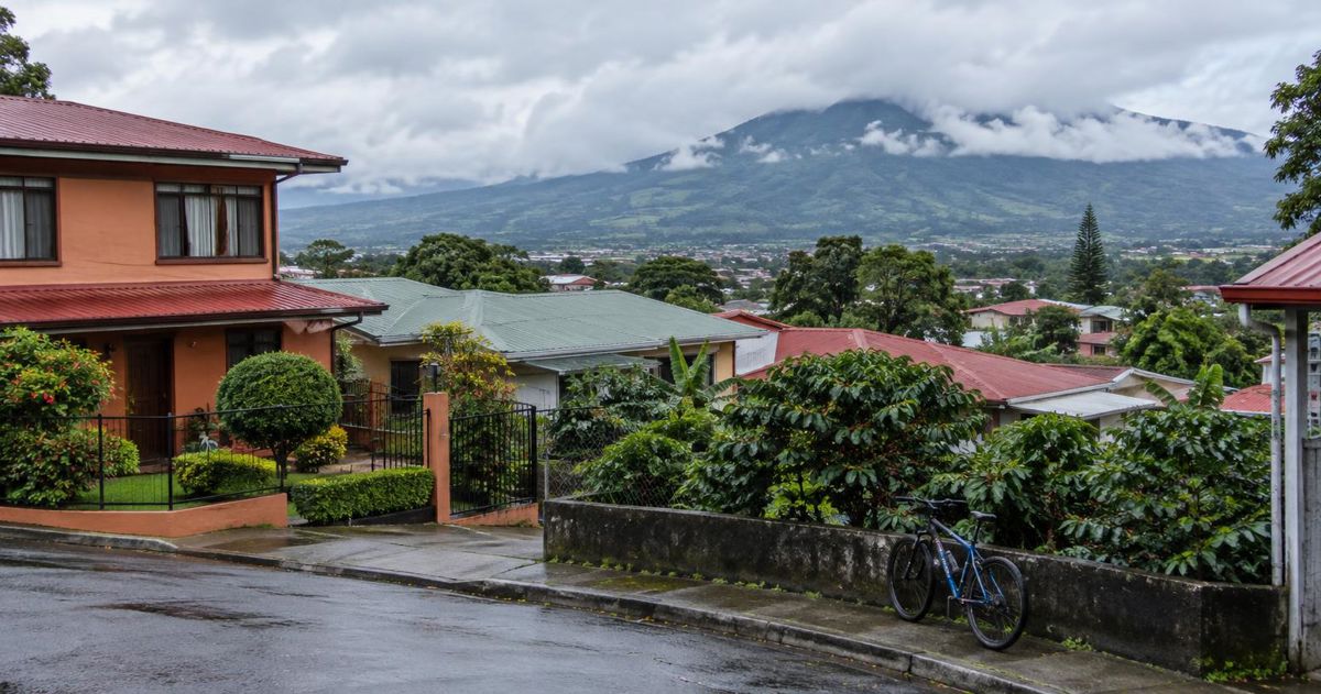 Barrio residencial de Heredia visto desde una calle en alto, con techos de colores, árboles y cerros al fondo