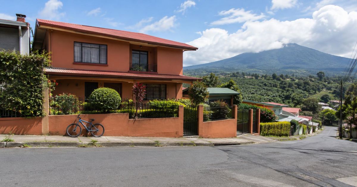 Street corner on a sloping road with a terracotta-fronted house in Heredia province, Costa Rica